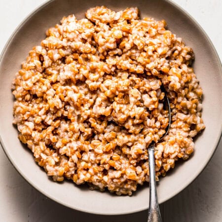 Overhead shot of cooked instant pot farro in white bowl with serving spoon.