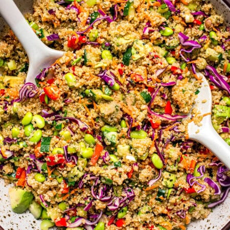 Overhead shot of Prepared asian quinoa salad in bowl with serving tongs.