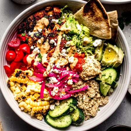 Overhead shot of assembled harissa chicken bowl with slices of pita.