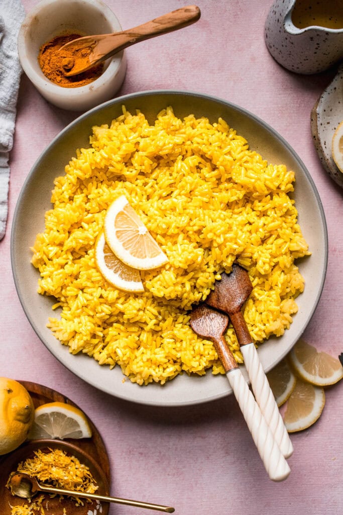 Overhead shot of greek lemon rice in serving bowl topped with lemon wedges.